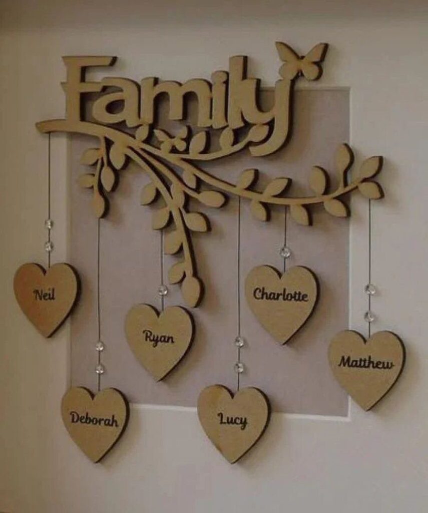 Wooden family wall art with a branch and heart pendants engraved with names.