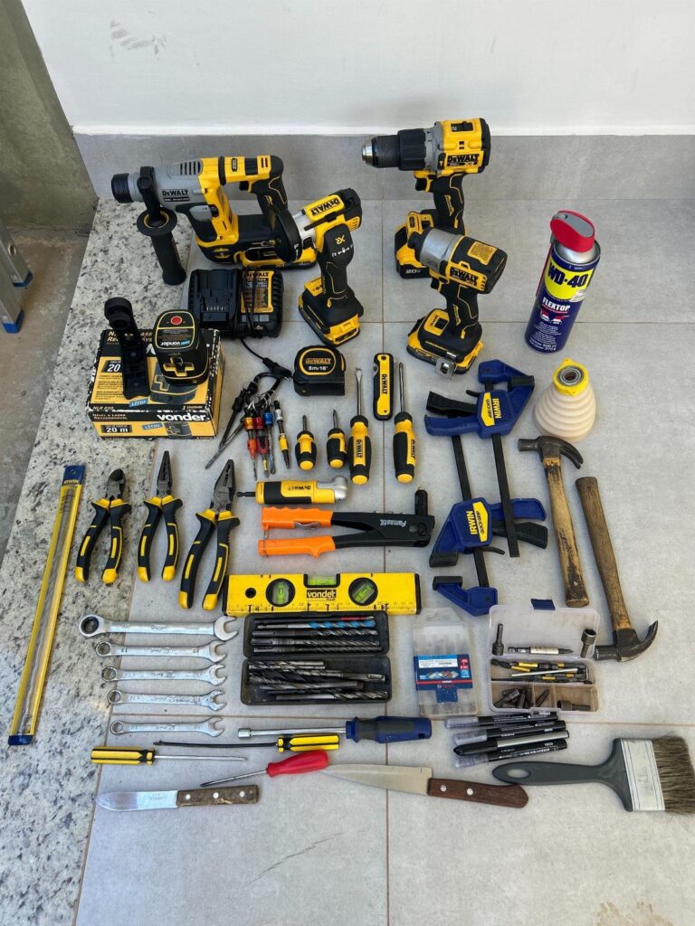 Assorted carpentry tools and power drills arranged on a light grey tiled floor.