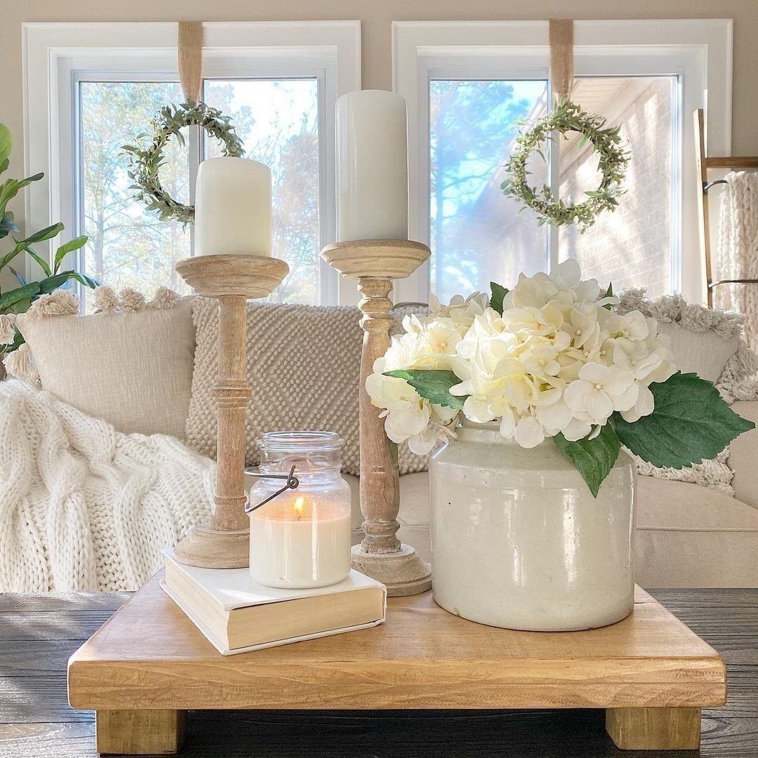 Wooden riser platform holding white candles and a vase of white hydrangeas.