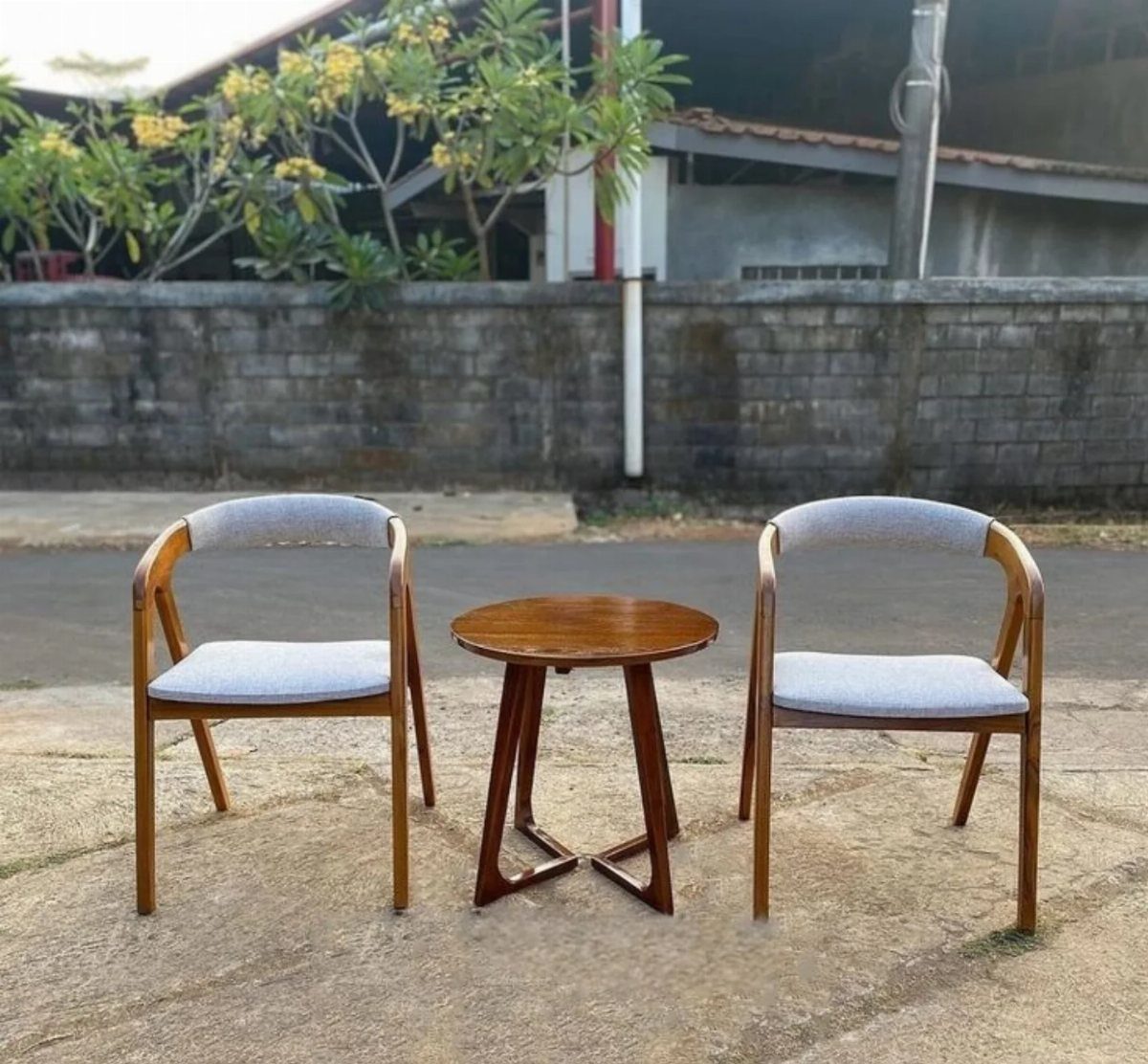 Two wooden armchairs with grey cushioned seats and a small round wooden table.