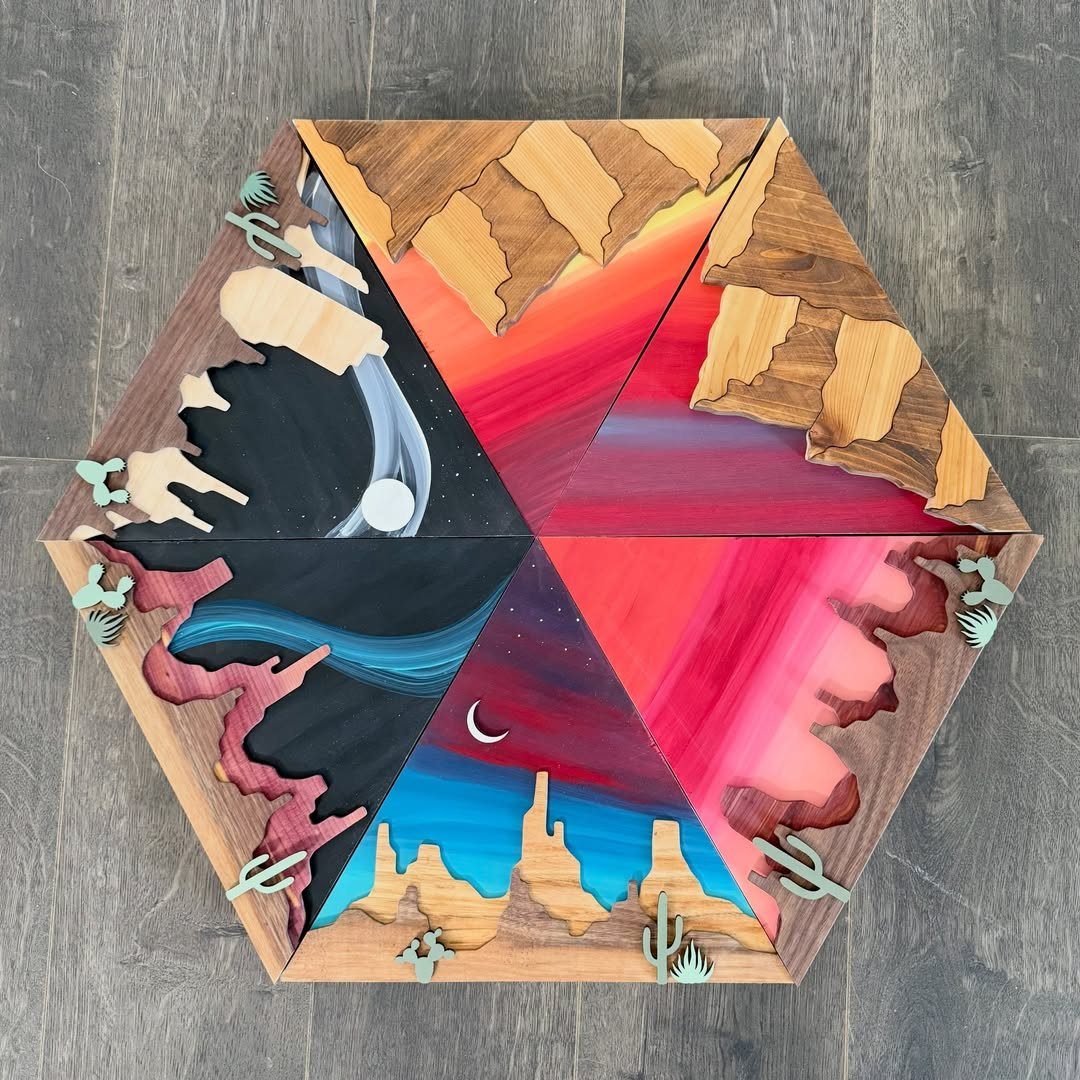 Hexagonal layered wood art depicting a colorful desert landscape with mountains and cacti.