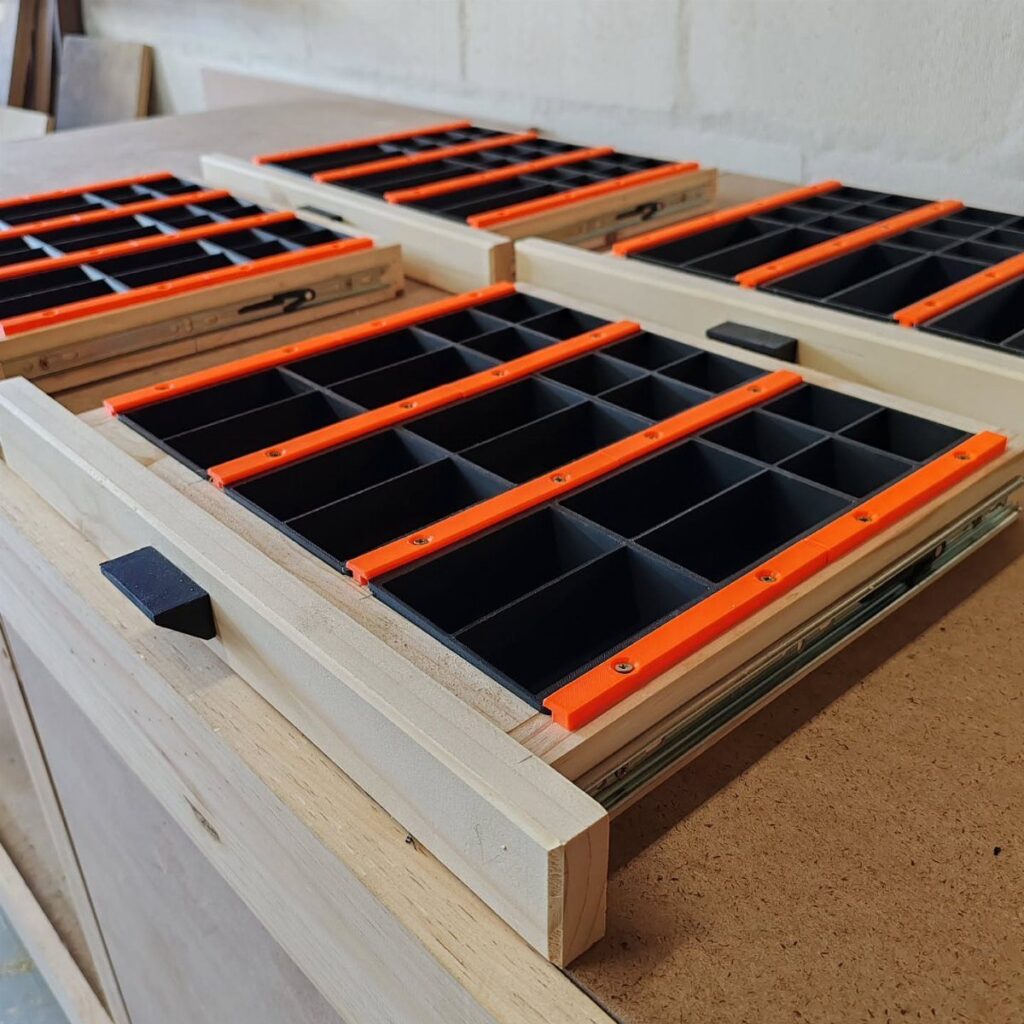 Wooden drawers with black foam and orange dividers for organizing small workshop tools.