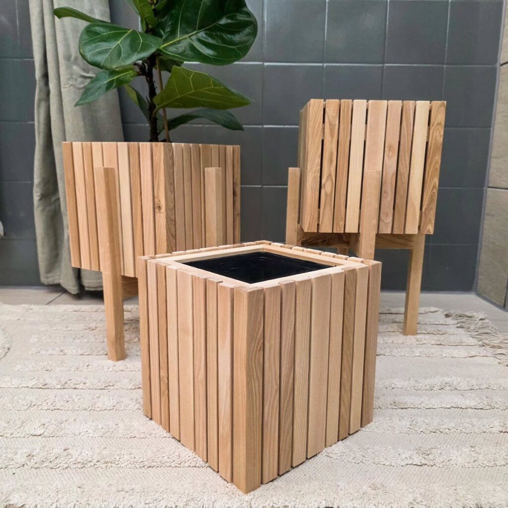 Three light wood plant stands of different heights on a white textured rug.