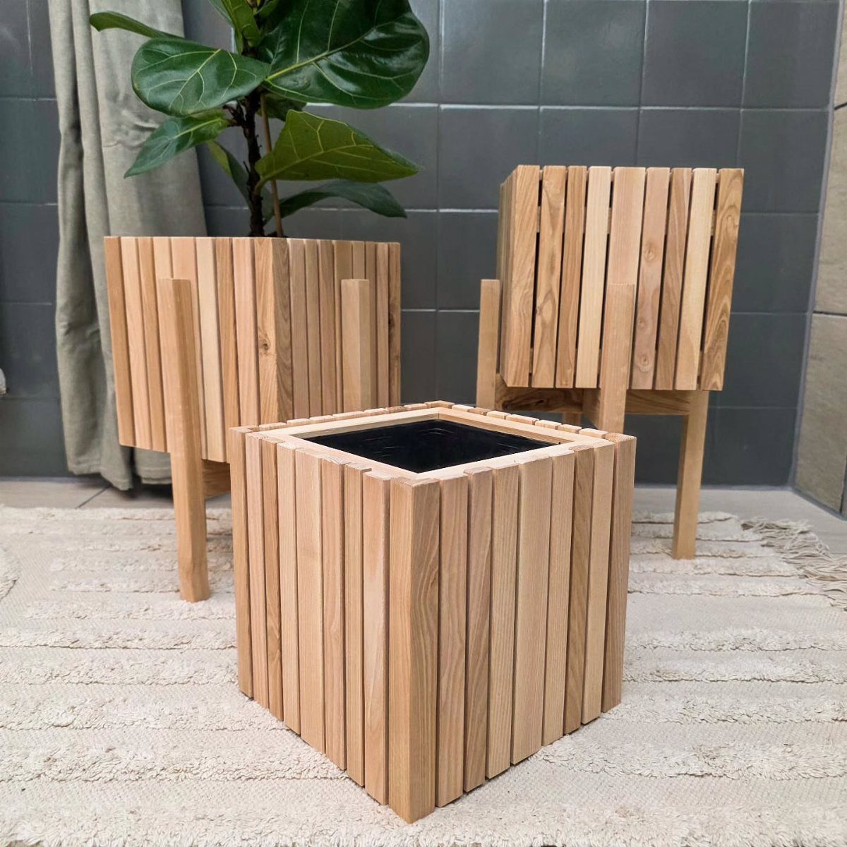 Three light wood plant stands of different heights on a white textured rug.