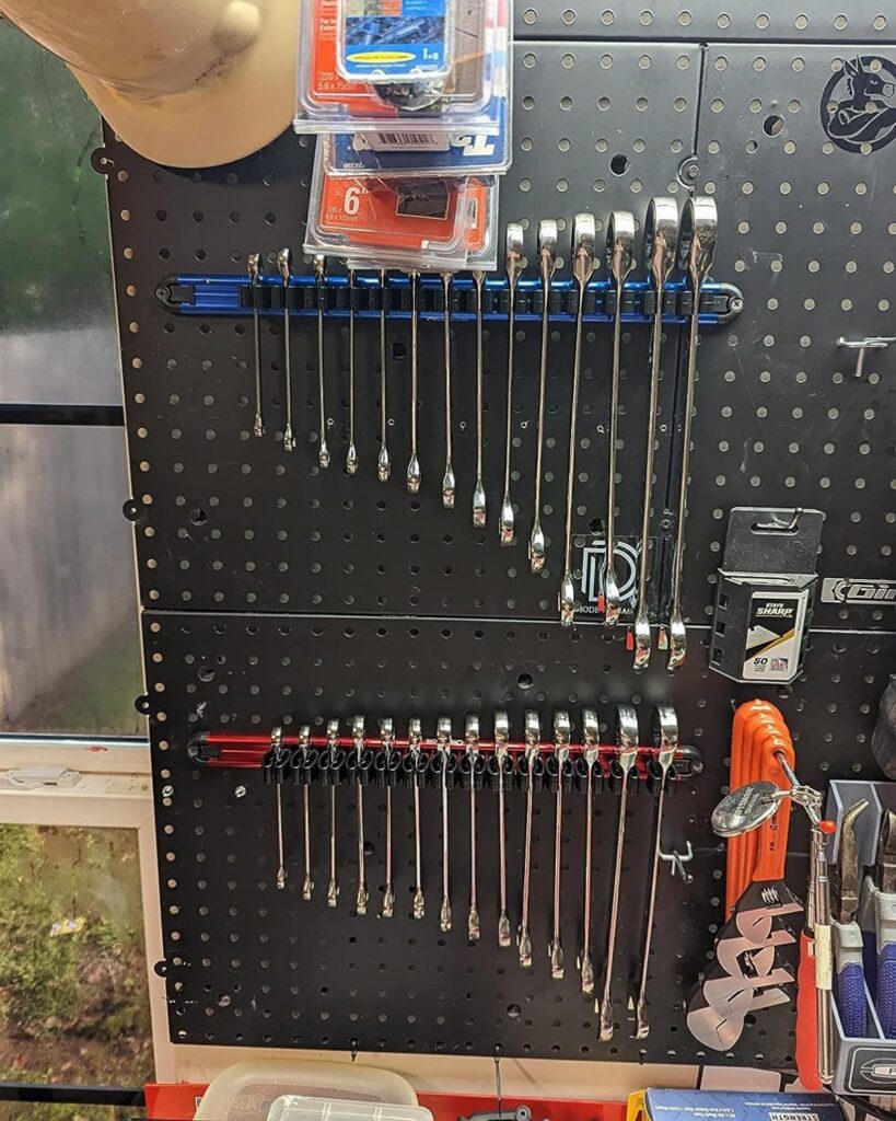 Black pegboard wall organizing silver wrenches on racks and small plastic storage bins.