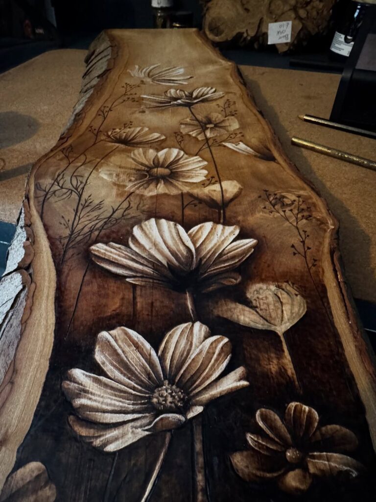 Detailed wood burned floral designs on a natural edge wooden slab