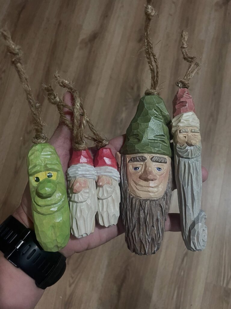 Hand-carved wooden ornaments of bearded figures and a green character with twine loops.