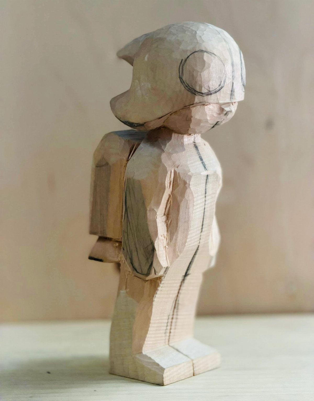 Hand-carved wooden character figure with a helmet and backpack on a plain background