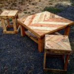 Chevron pattern pallet coffee table with two matching wooden stools on dark gravel.