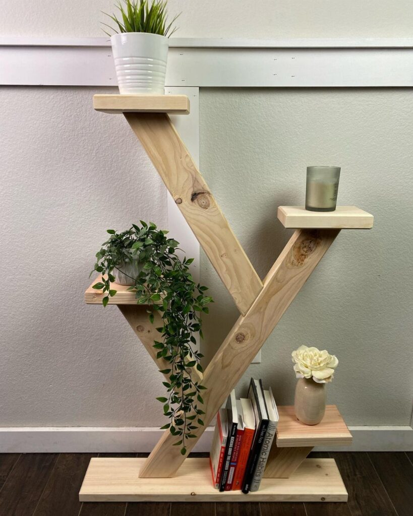 Geometric wooden plant stand with multiple shelves holding greenery and decorative home items.