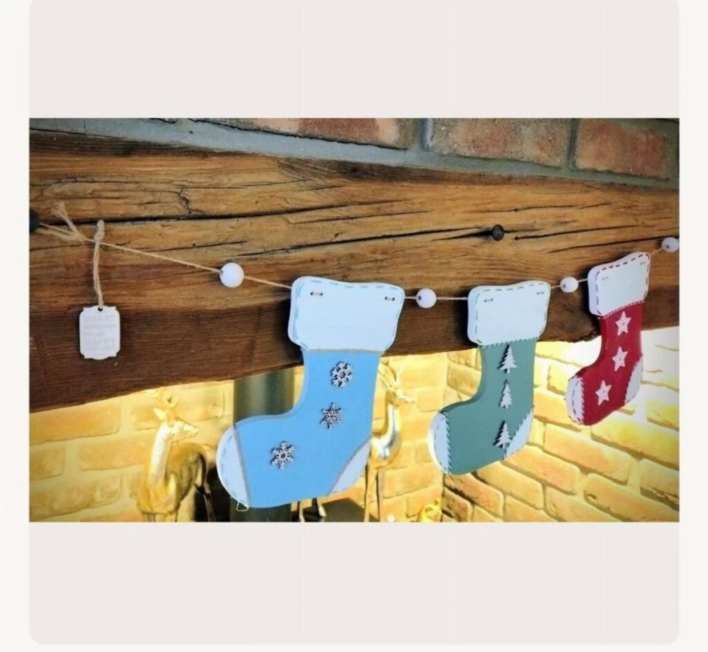 Wooden Christmas stockings in blue, grey, and red hanging from a twine string.