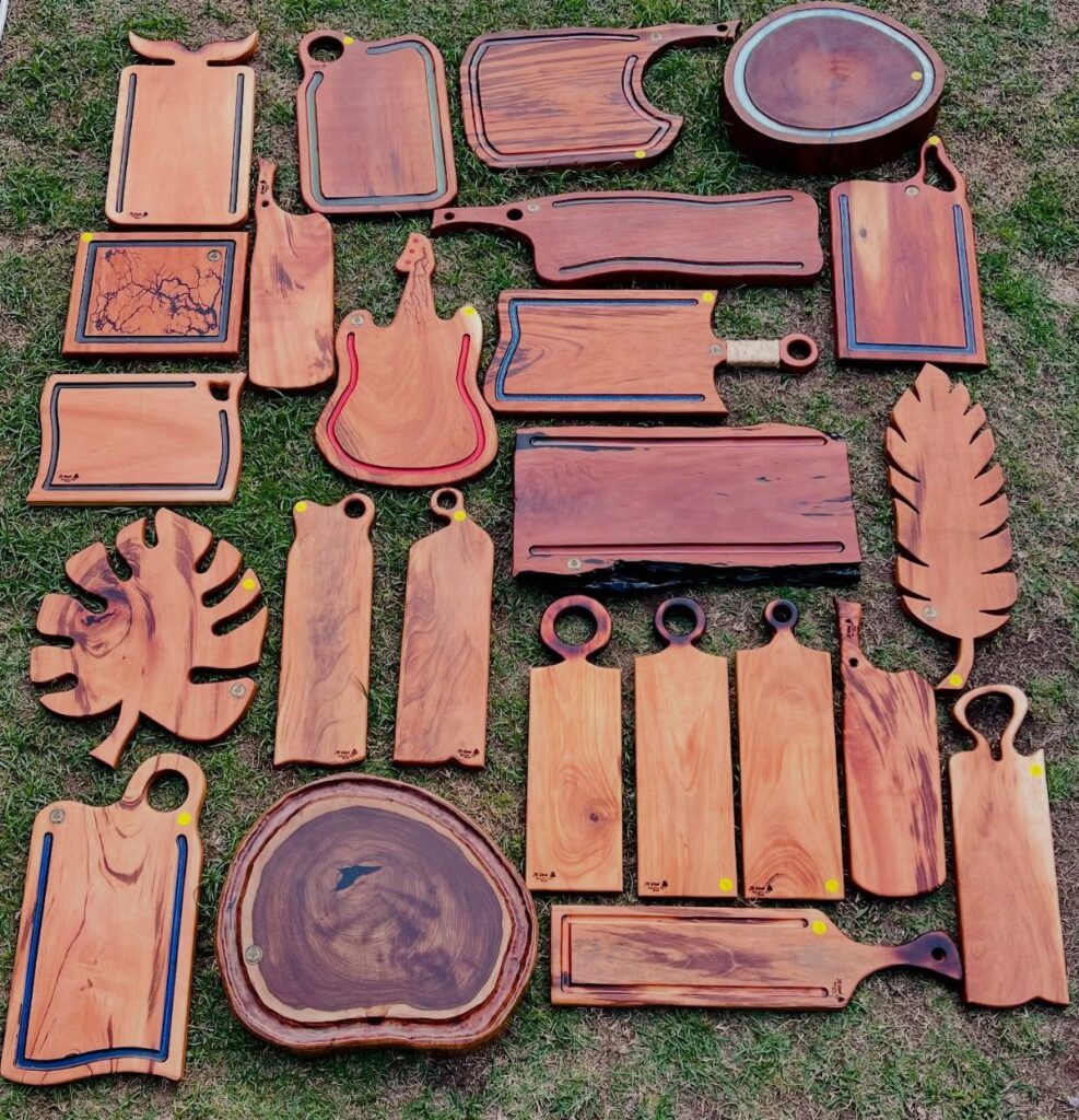 Various shaped wooden cutting boards and serving platters arranged on a green grass lawn.