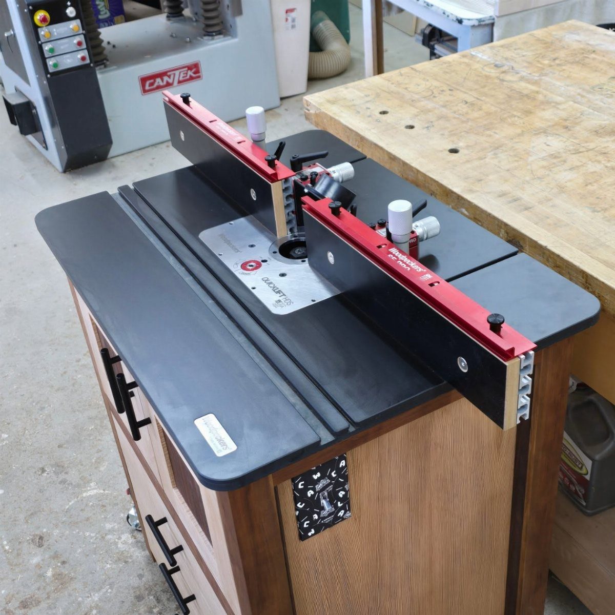 Woodpeckers router table with red fence on a wooden cabinet in a workshop.
