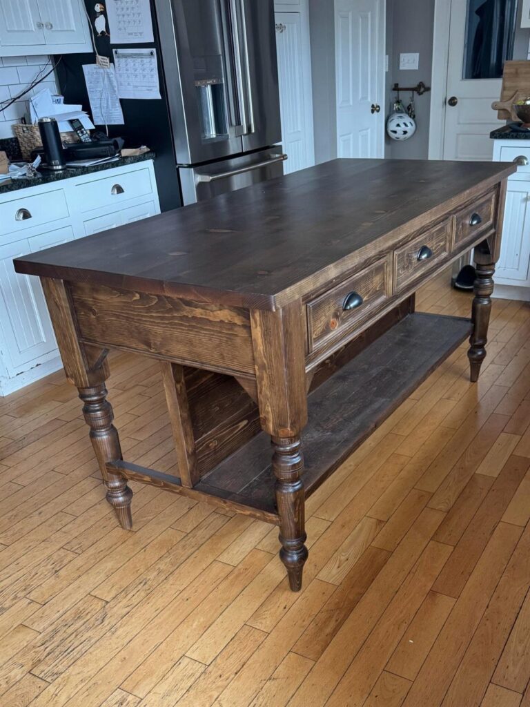 Dark brown wooden kitchen island with drawers and a lower shelf on hardwood floors.