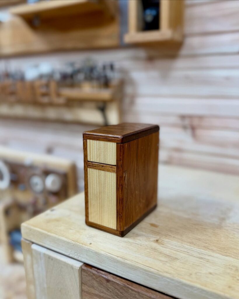 Small rectangular wooden box with contrasting light and dark wood on a workbench.