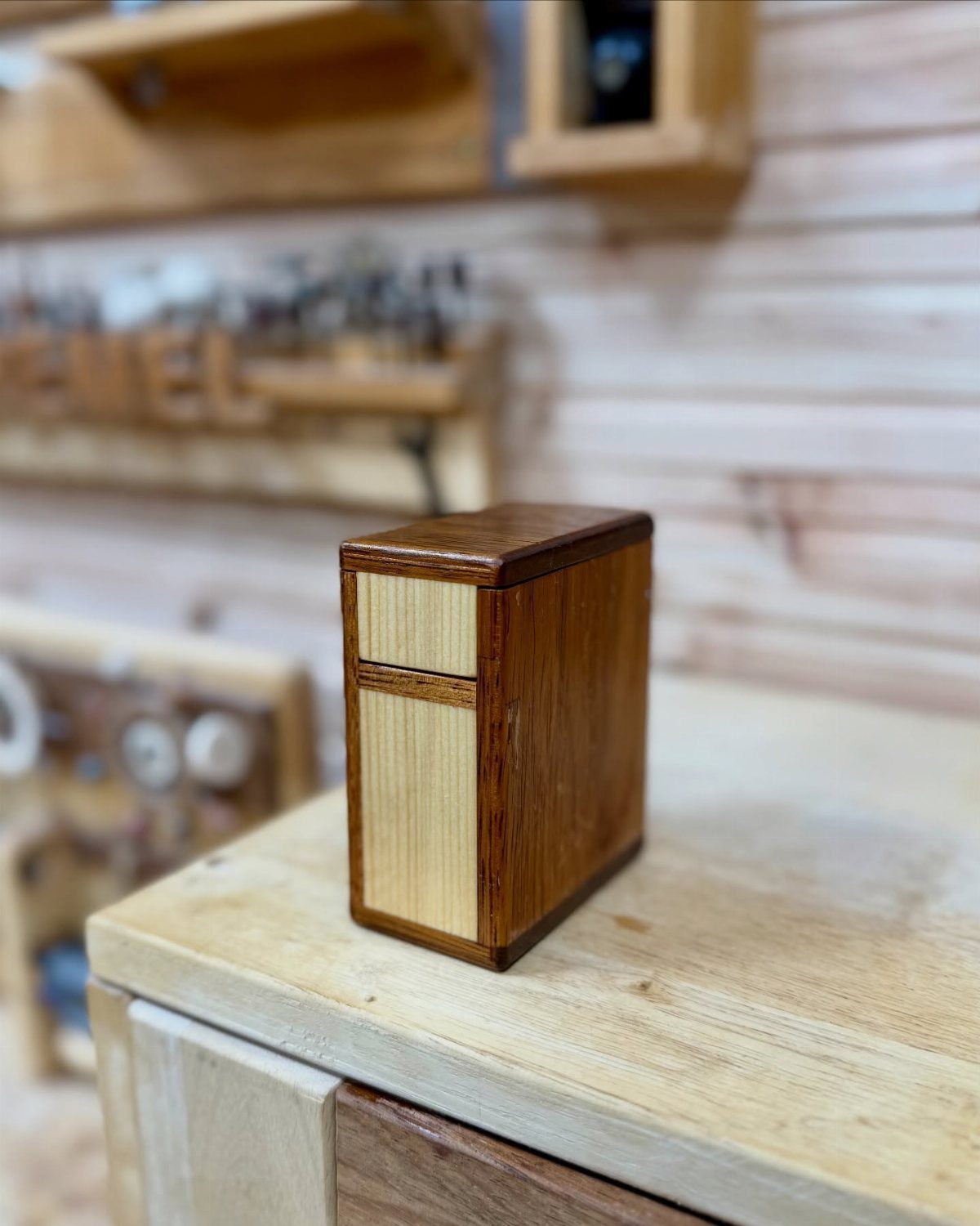 Small rectangular wooden box with contrasting light and dark wood on a workbench.